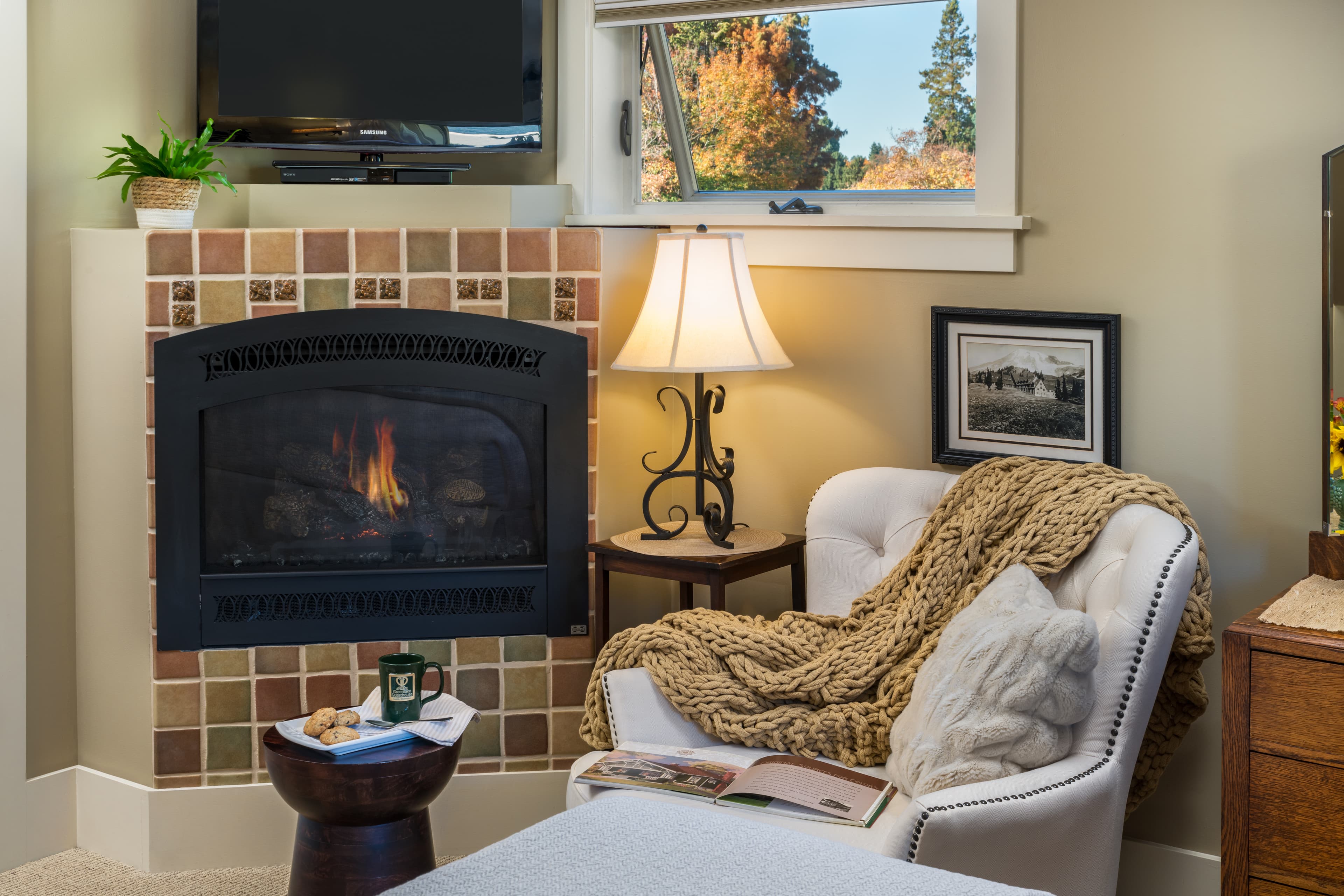 Cozy living room corner with armchair, fireplace, and a warm blanket.