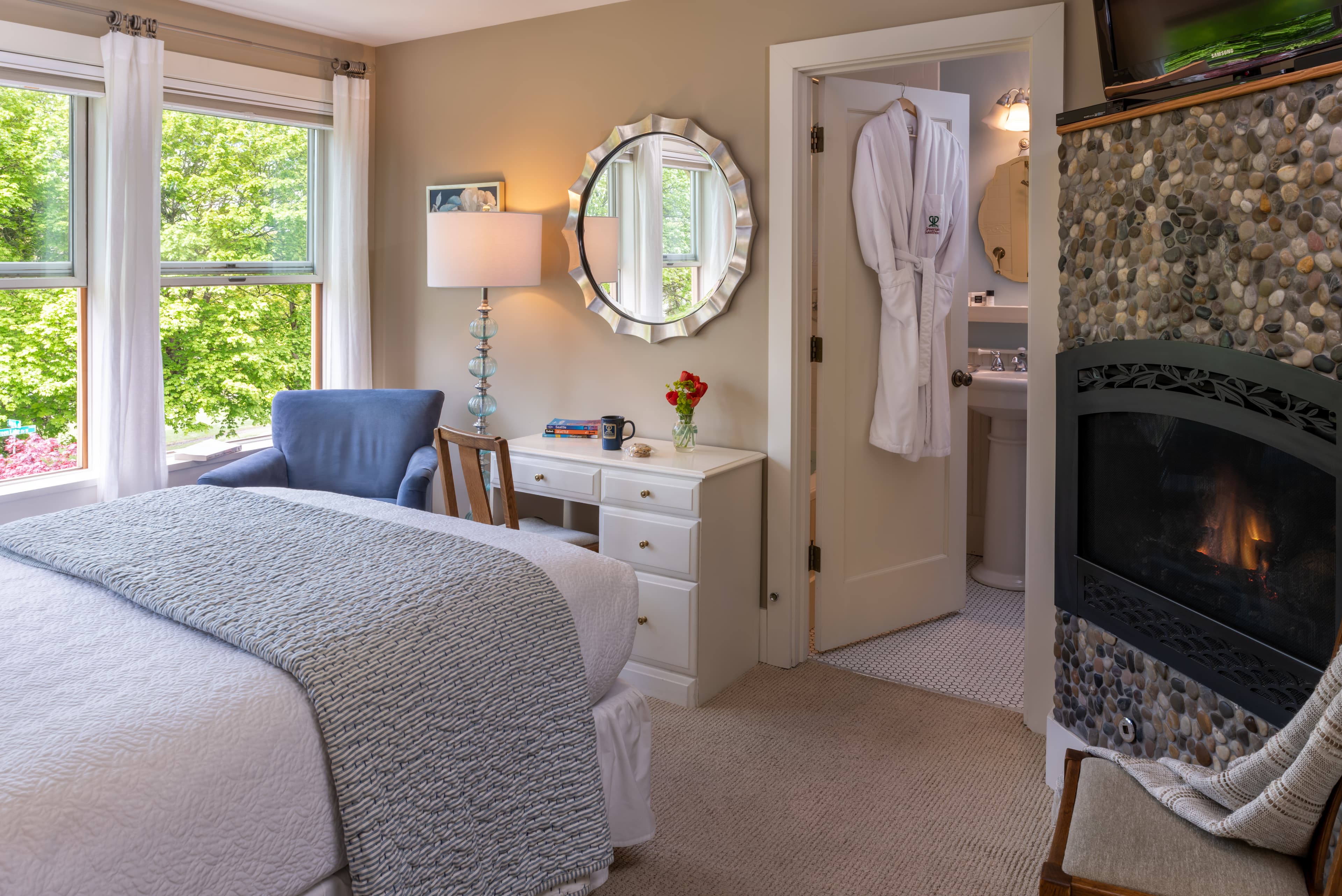Cozy bedroom with a fireplace, comfortable bed, and attached bathroom visible in the background.