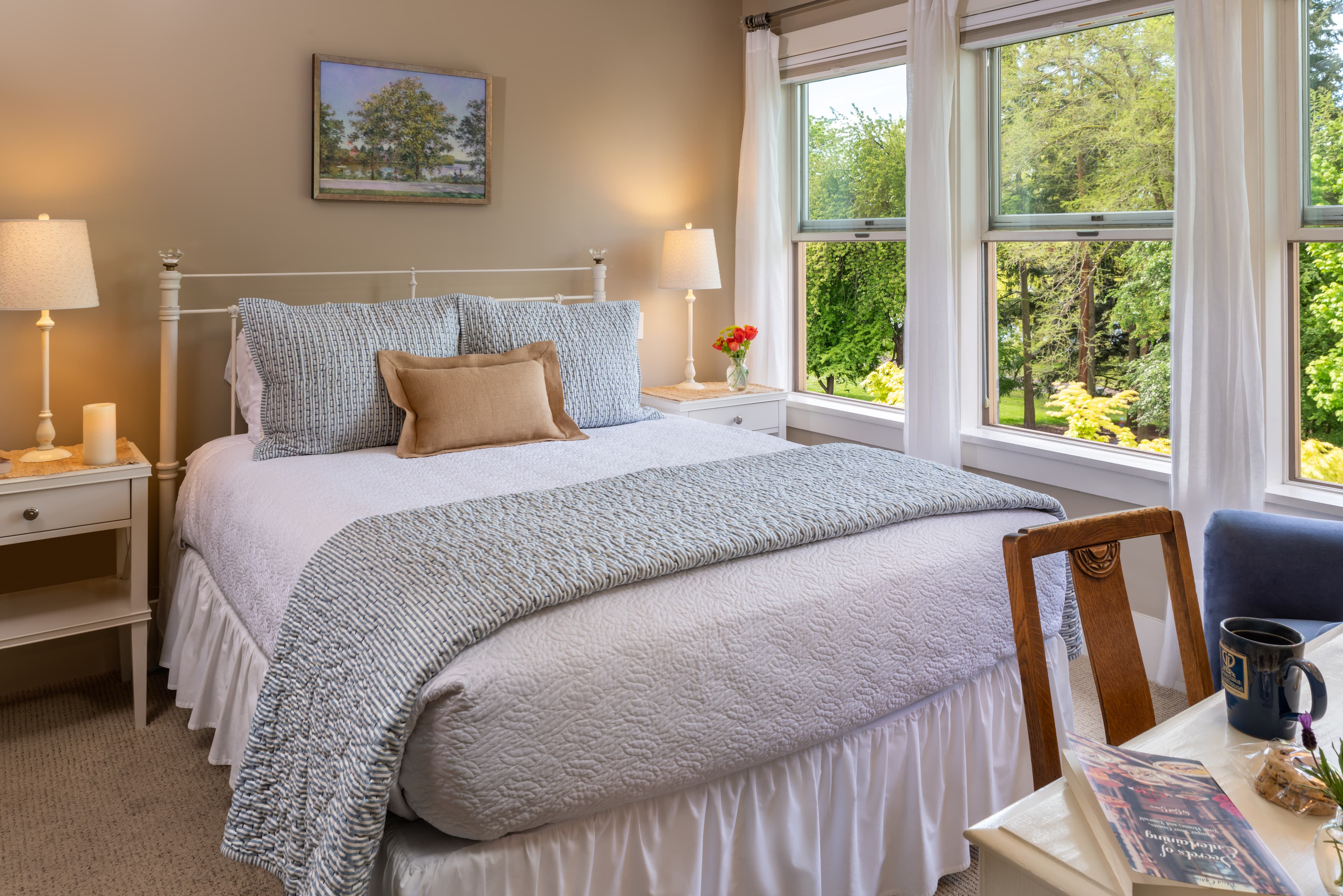 Cozy bedroom with a neatly made bed, two nightstands, lamps, and a wall painting.