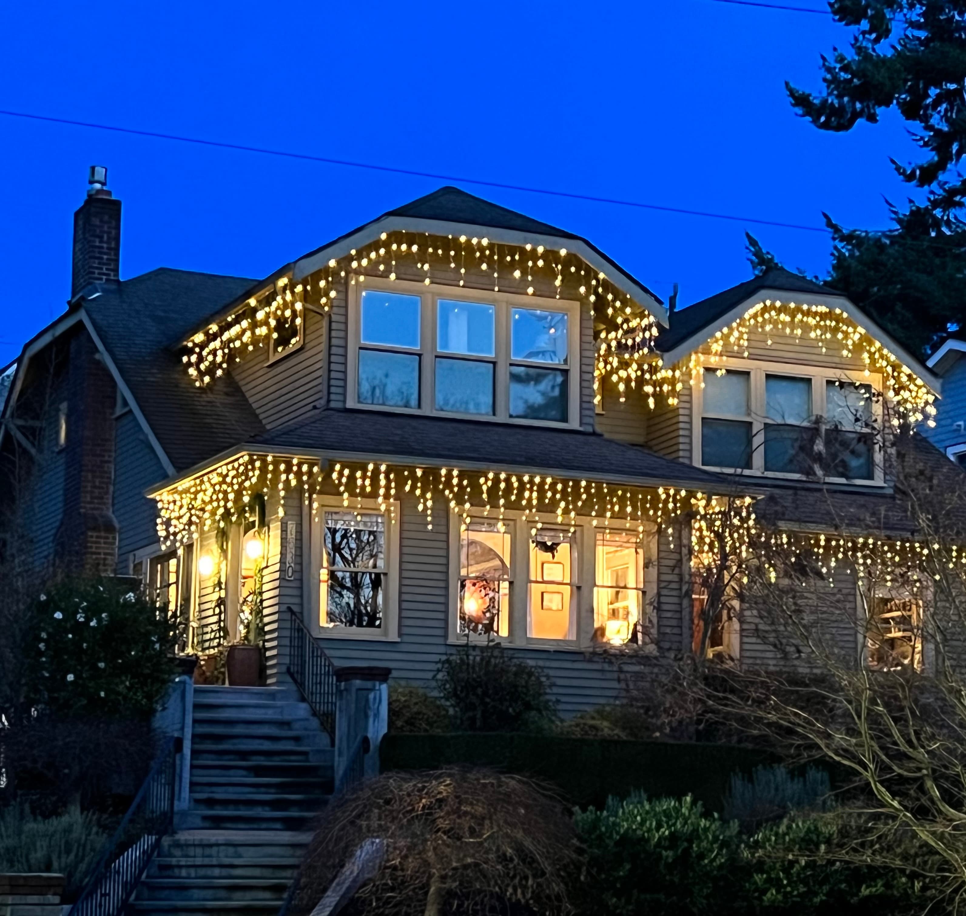 A cozy house illuminated with string lights against a twilight sky. A cozy house illuminated with string lights against a twilight sky.