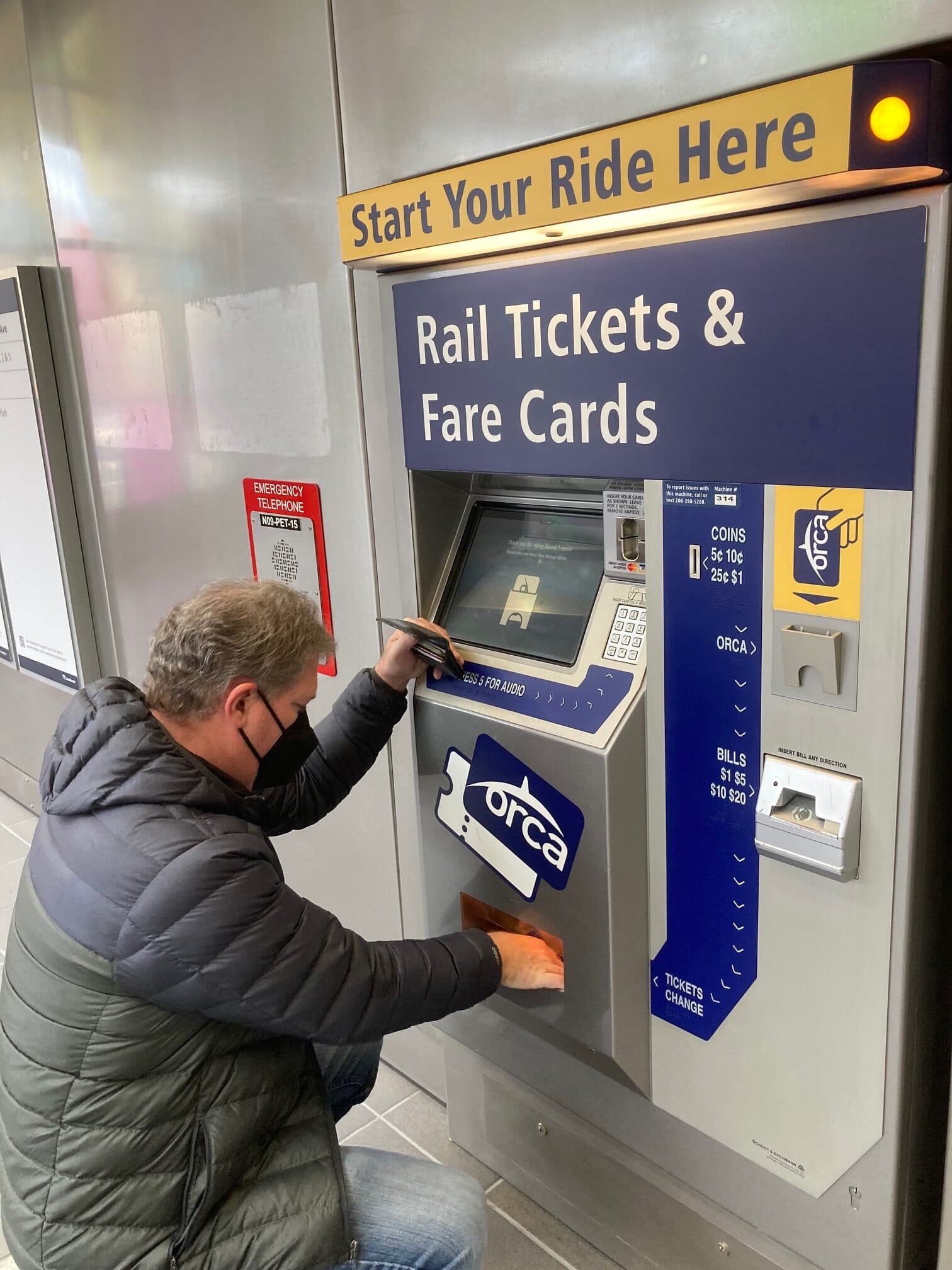 A person uses an ORCA card machine to purchase rail tickets and fare cards.