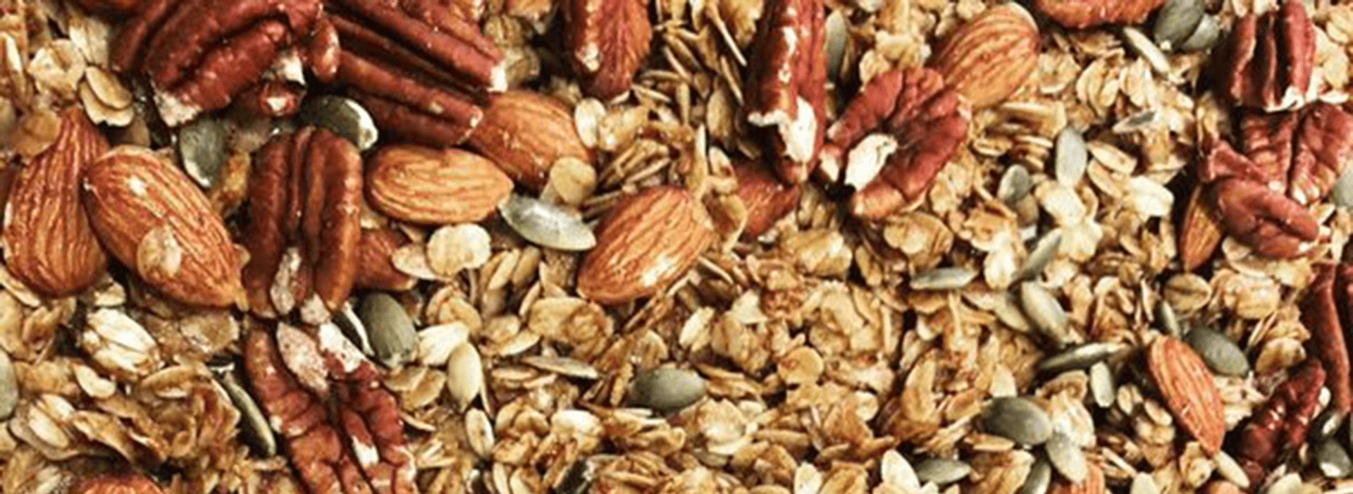 A close-up of a granola mix featuring oats, almonds, pecans, and pumpkin seeds.