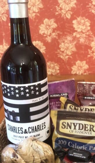 A bottle of Charles & Charles wine accompanied by snacks in a basket.