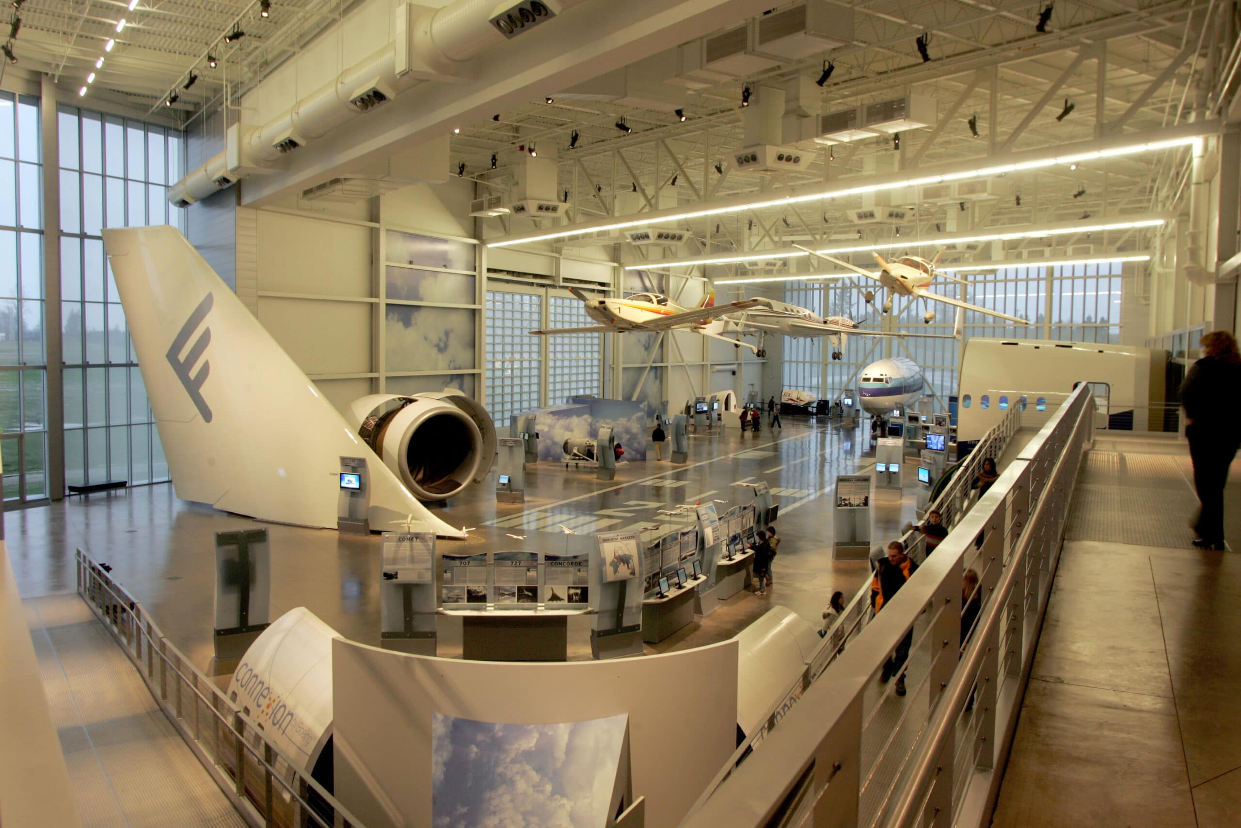 An interior view of an aviation museum featuring airplane exhibits and visitors exploring interactive displays.