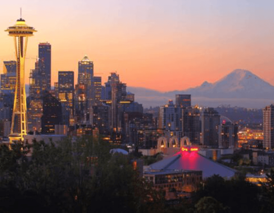 Seattle skyline at sunset, featuring the Space Needle and Mount Rainier in the background.