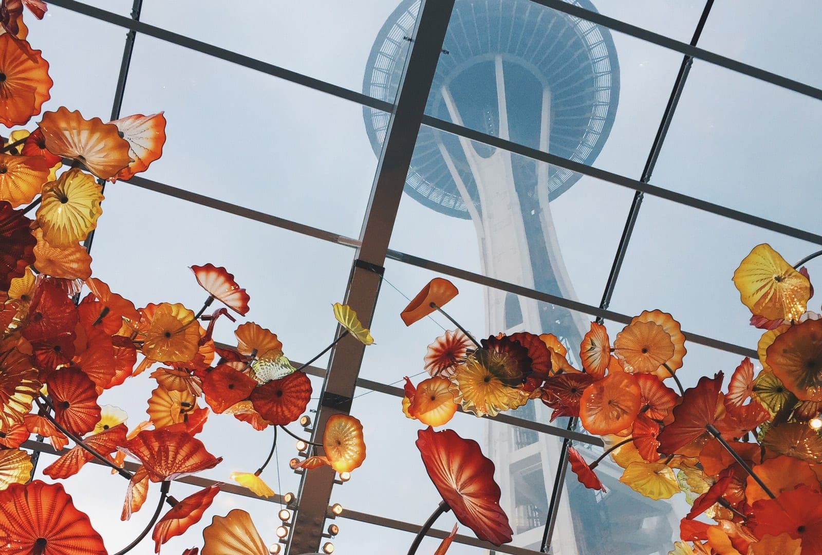 View of the Space Needle framed by vibrant orange and yellow floral decorations beneath a glass ceiling.