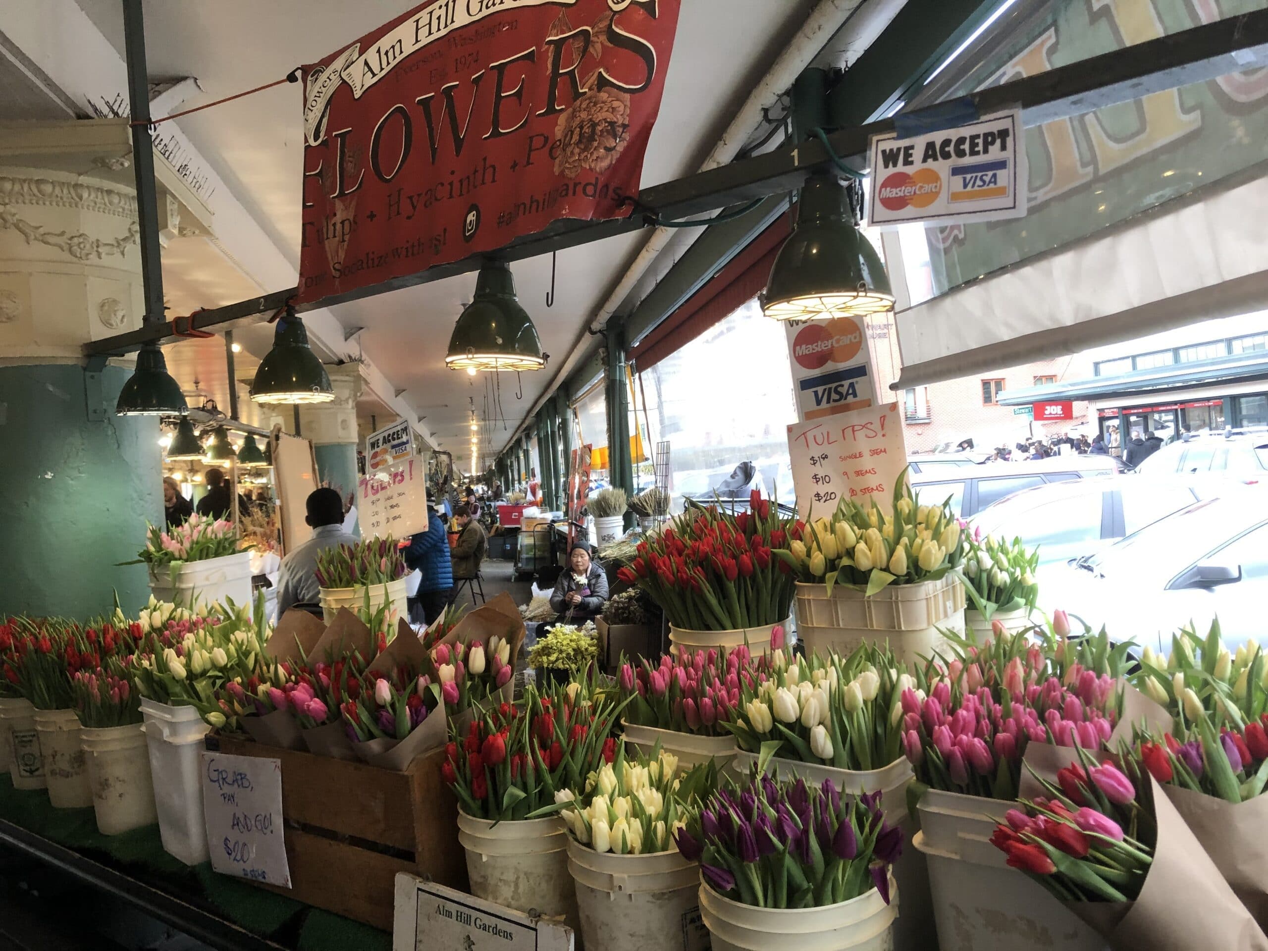 A flower stall filled with colorful tulips and a sign indicating payment options.