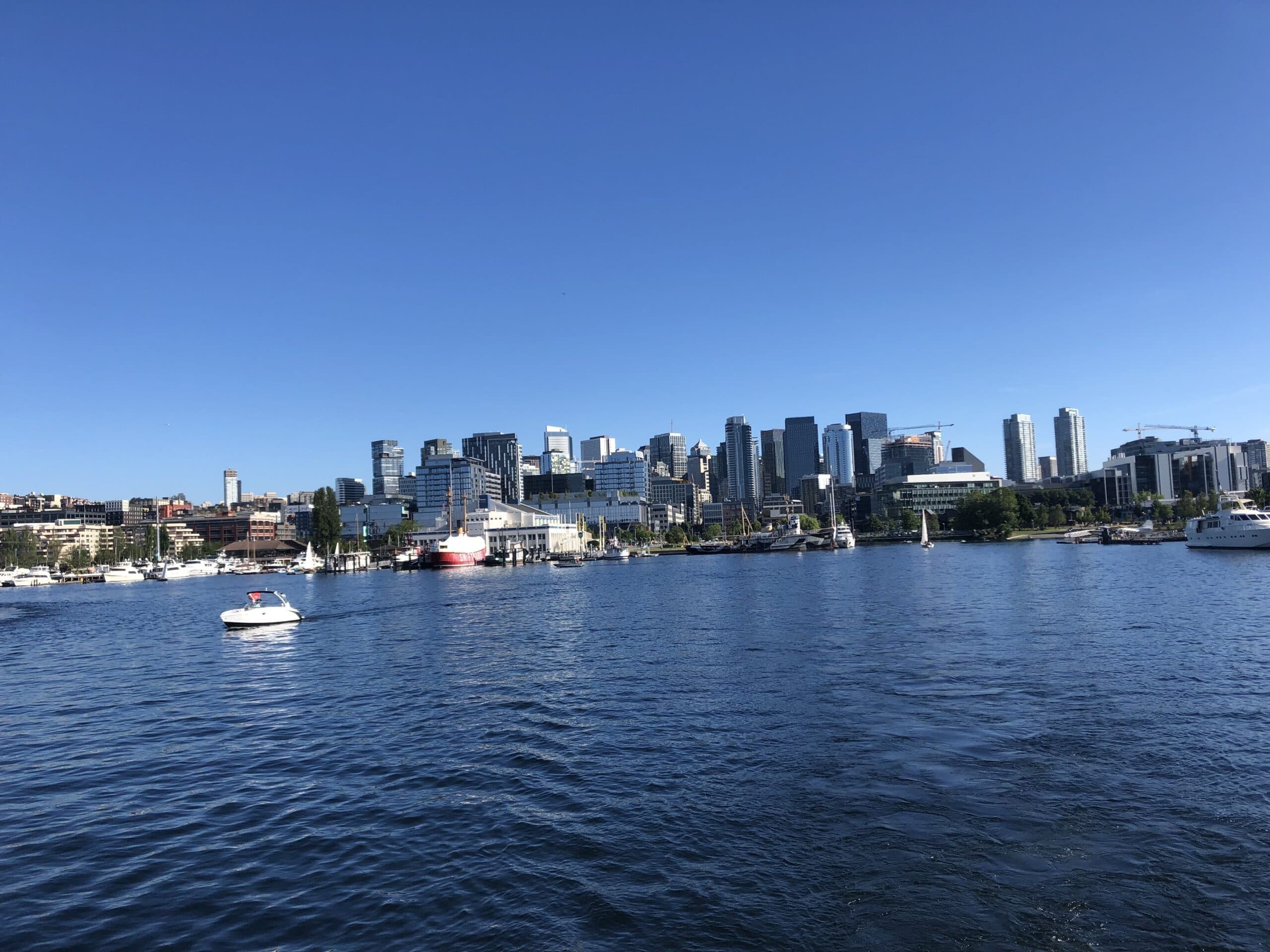 A view of a city skyline across a blue body of water under a clear sky.