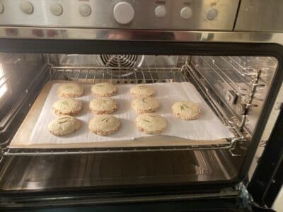 Cookies baking on a parchment-lined tray inside an oven.