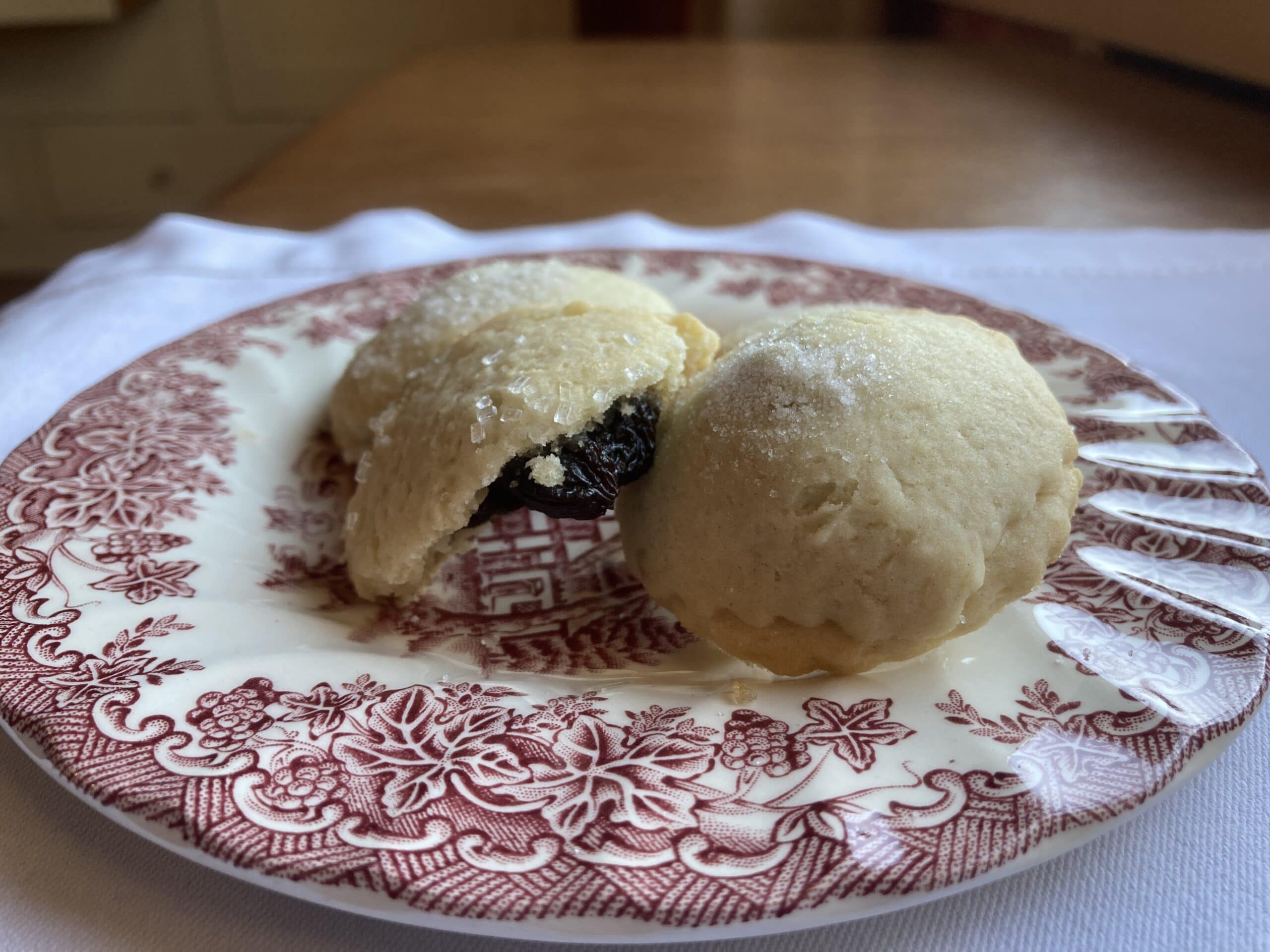 A plate featuring two dusted cookies, one split open to reveal a dark filling.