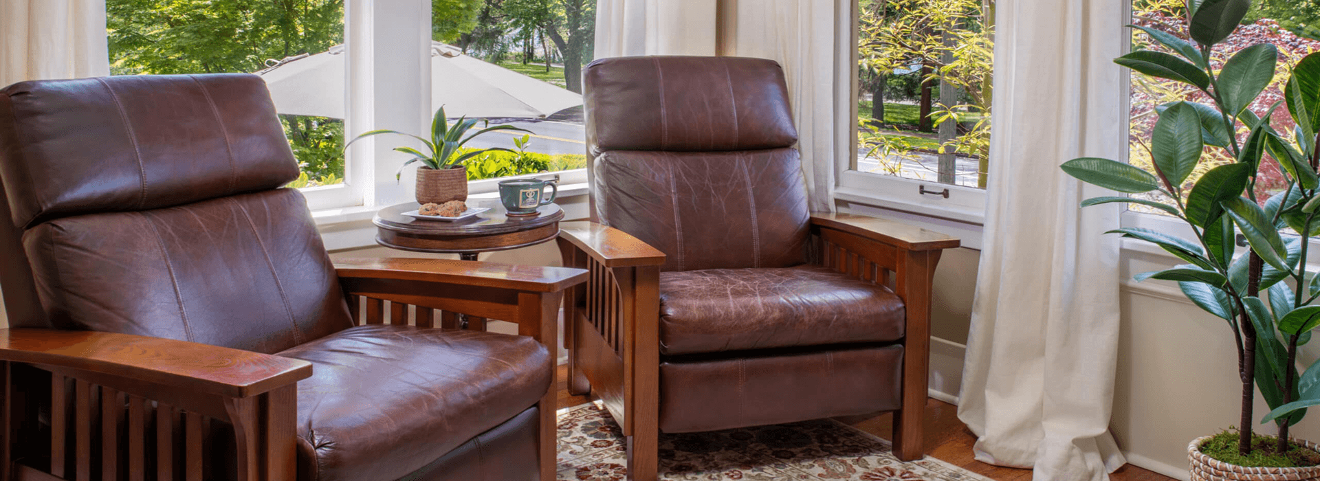 Cozy living space featuring two brown leather chairs, a potted plant, and a side table with snacks.