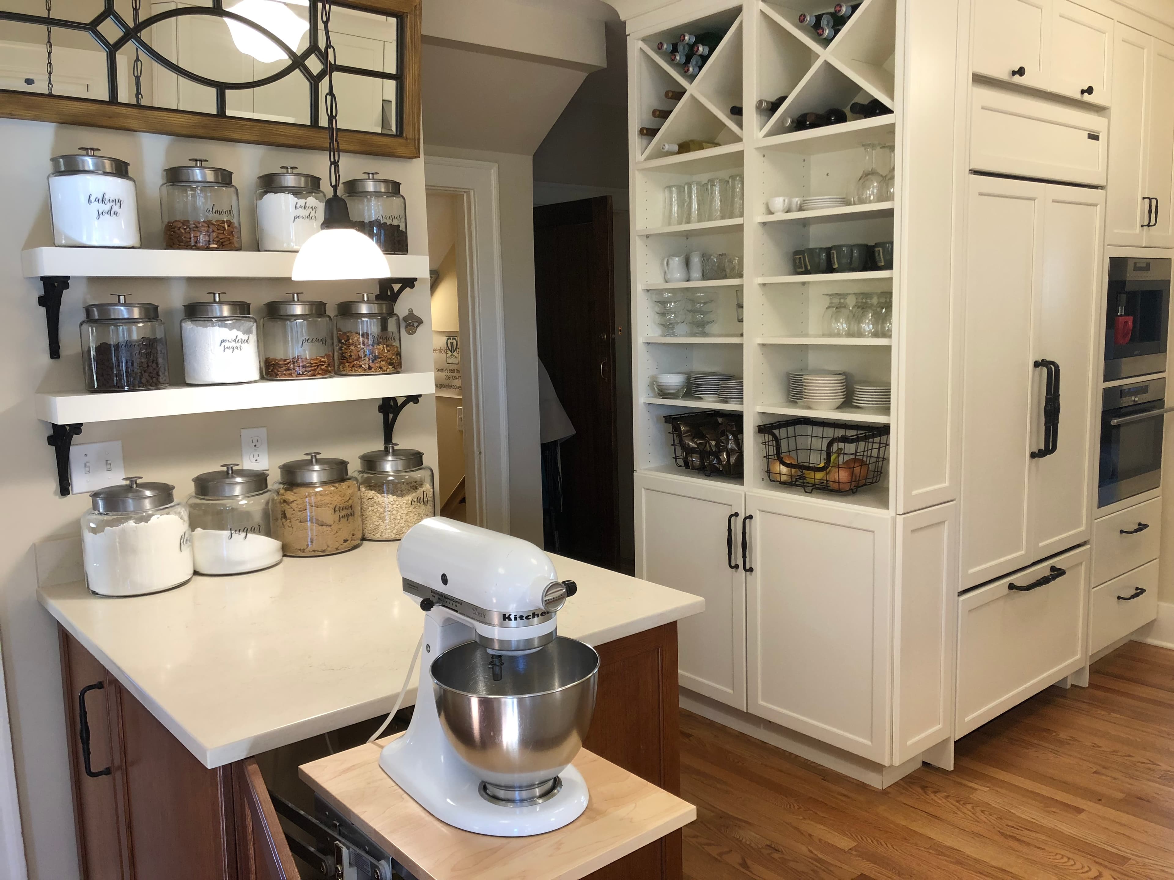 A modern kitchen featuring a stand mixer, organized shelves with glass jars, and a tidy pantry.