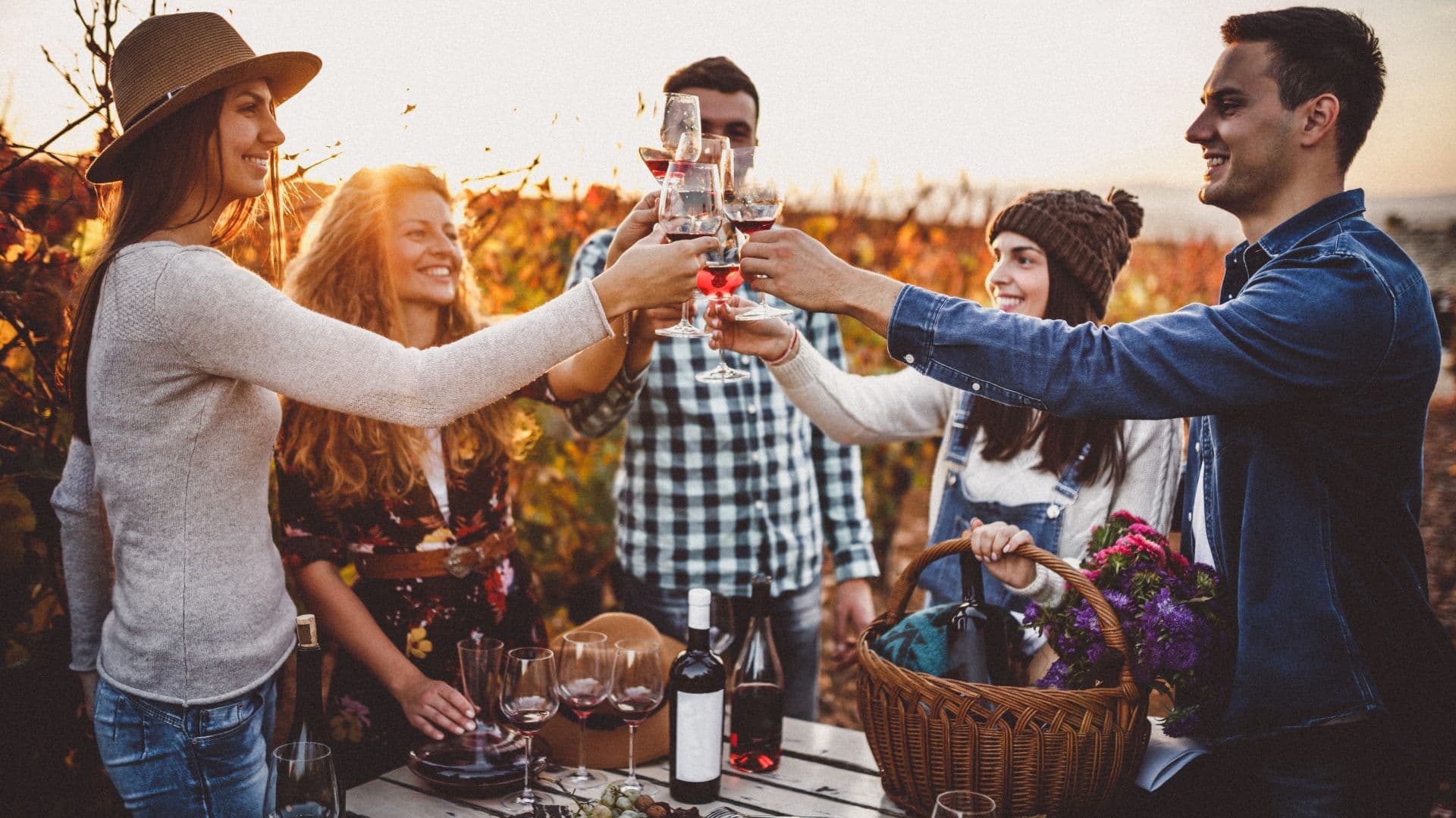 A group of friends toasting with glasses of wine in a vineyard during sunset. A group of friends toasting with glasses of wine in a vineyard during sunset.
