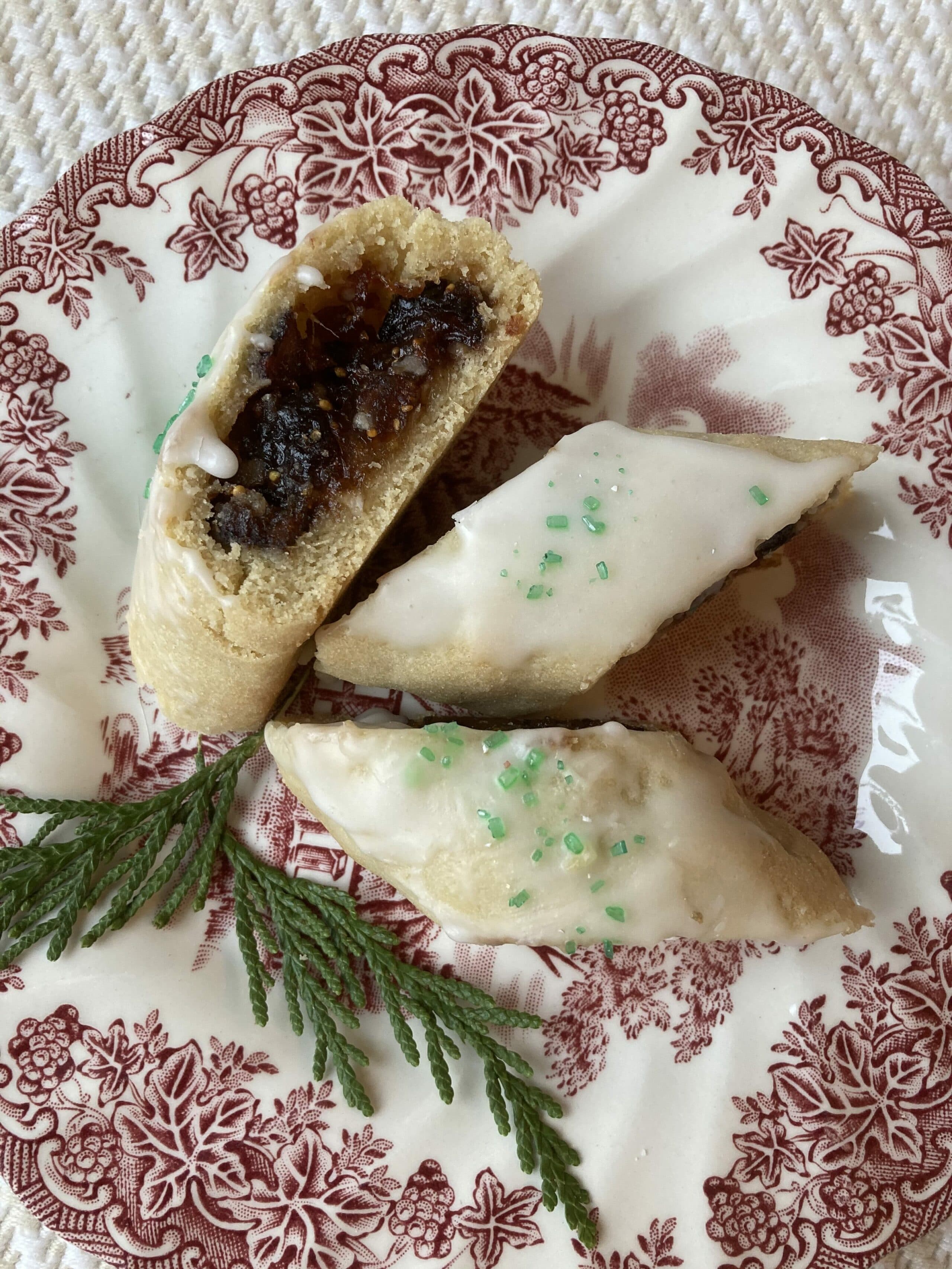 A plate of decorated pastries, including one cut in half, revealing a sweet filling.