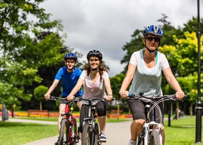 Three friends enjoy biking together on a sunny park path.