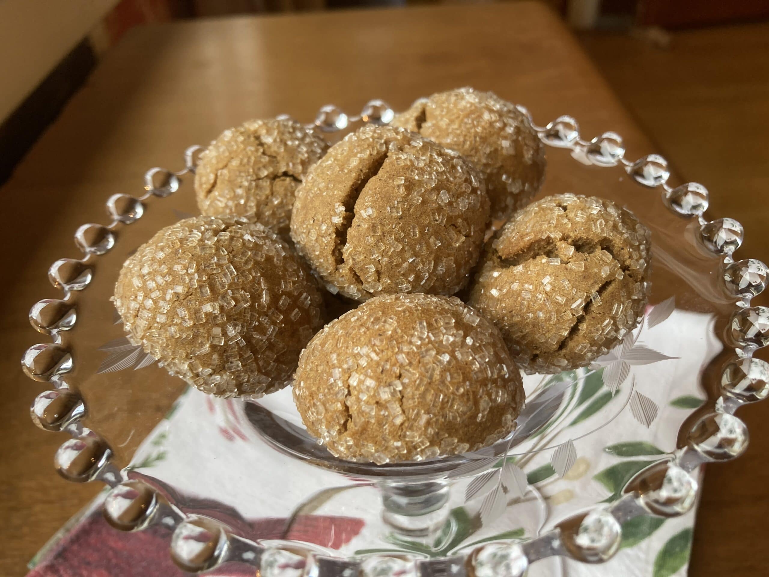 A clear glass dish holds six sugar-coated, cracked spherical confections.