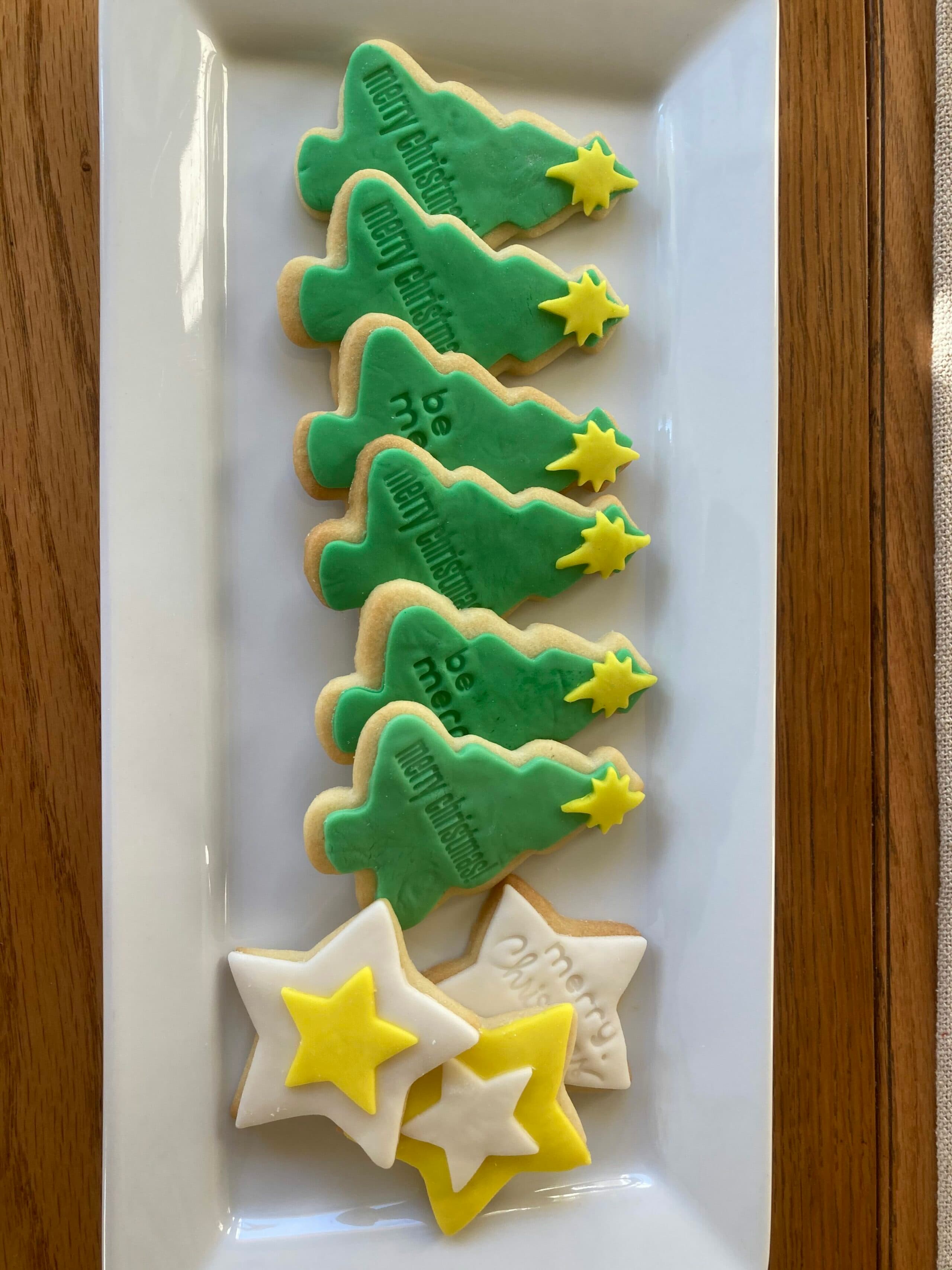 A plate of green Christmas tree and star-shaped cookies with festive decorations.