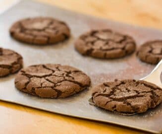 A tray of freshly baked chocolate cookies with a cracked surface.