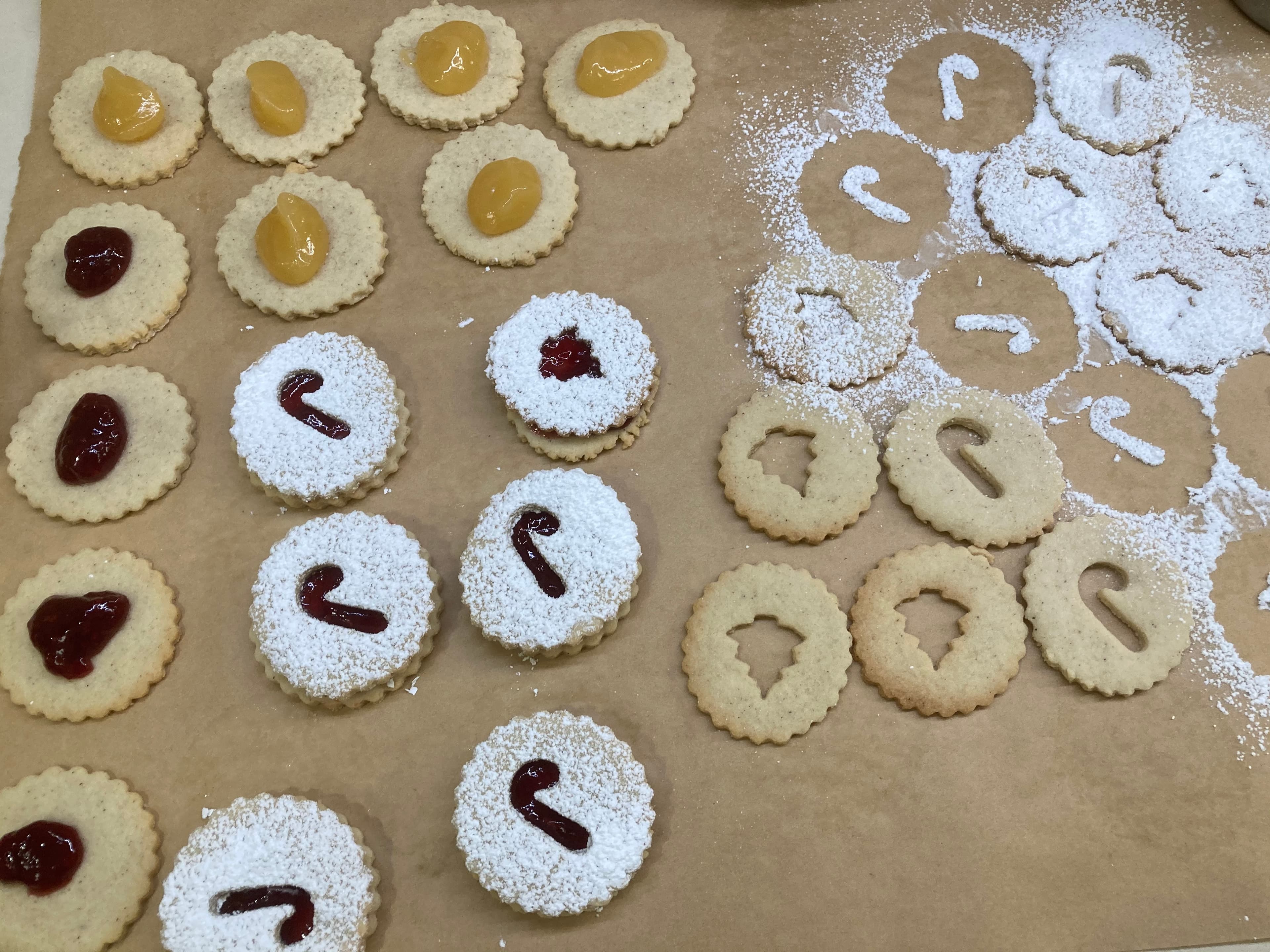A tray of assorted cookies, some filled with jam and others dusted with powdered sugar.