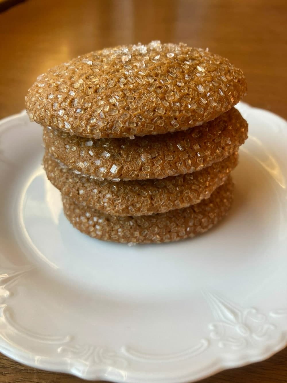 A stack of golden-brown, sugar-coated cookies on a white plate.