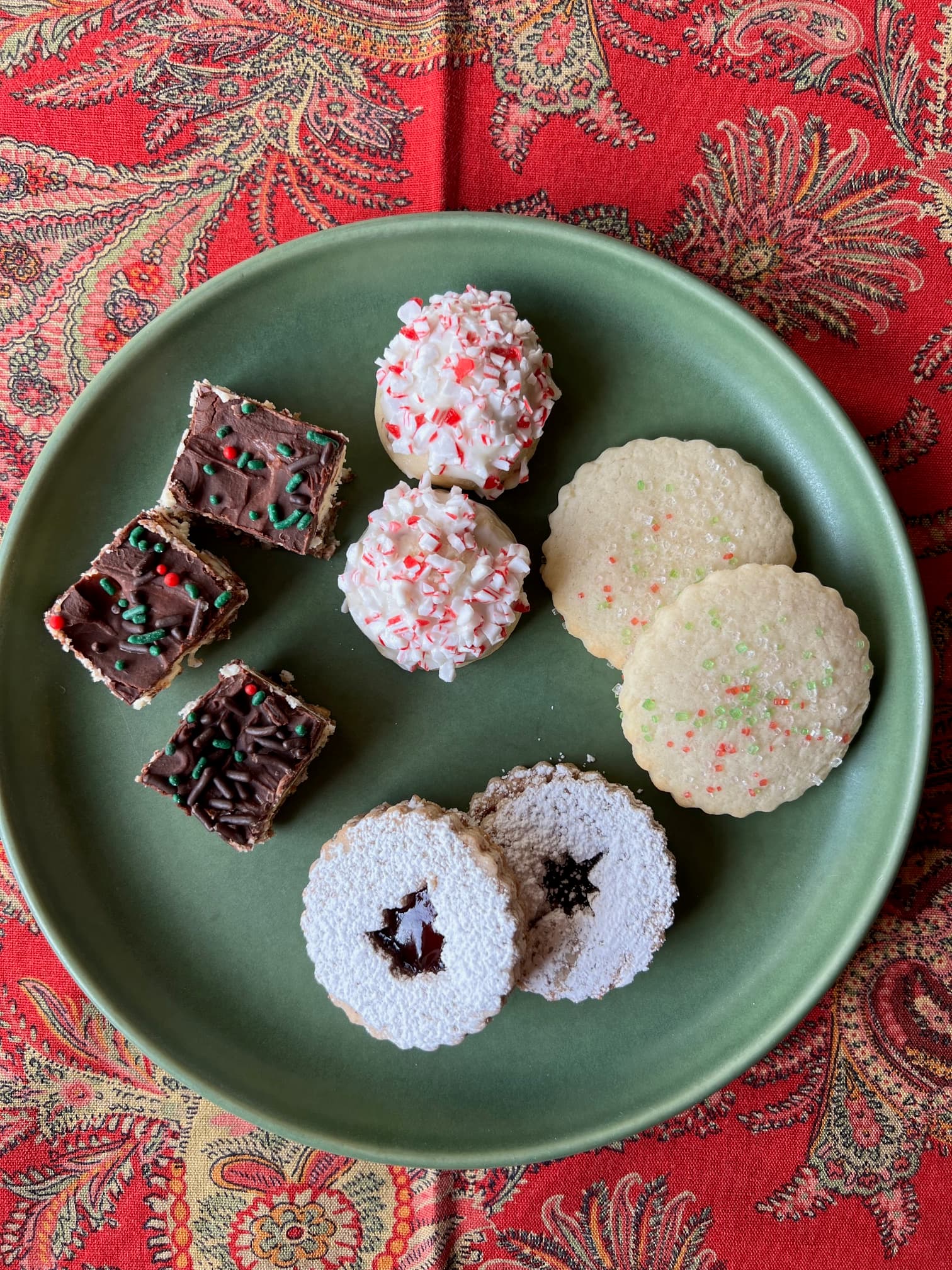 A green plate displaying an assortment of festive holiday cookies and treats. A green plate displaying an assortment of festive holiday cookies and treats.