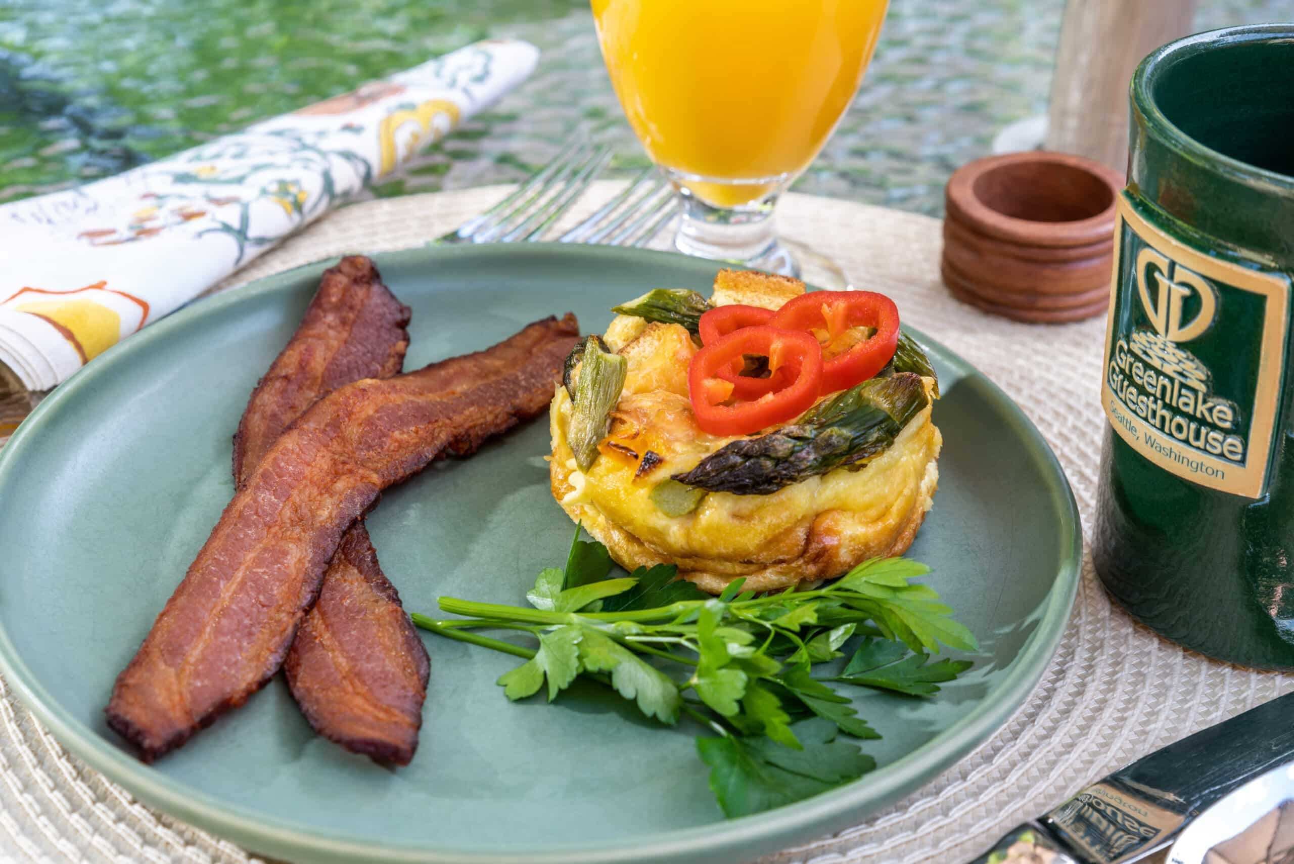 Colorful breakfast plate with egg strats and bacon, orange juice, coffee