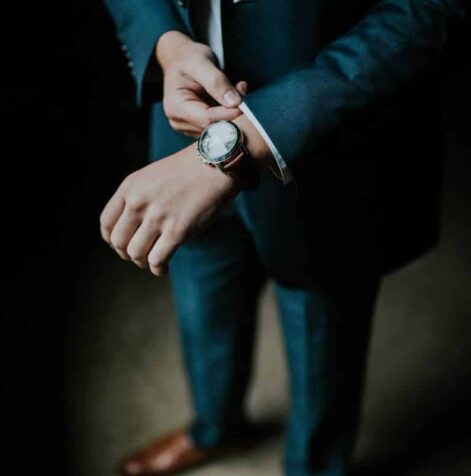 Business man adjusts his watch and the collar of his suit