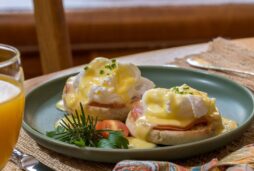 Eggs benedict with orange juice and coffee on green dishes