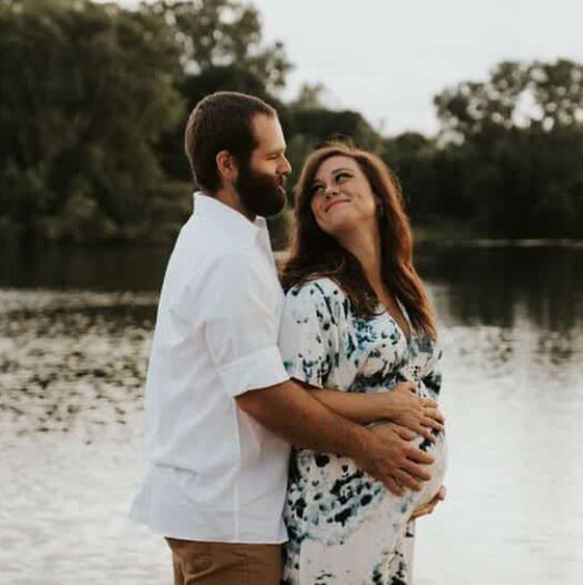 couple expecting a baby with man holding women's stomach as she looks back at him