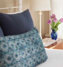 Pillows rest on the end of the bed and a bouquet of beautiful tulips is on the dresser